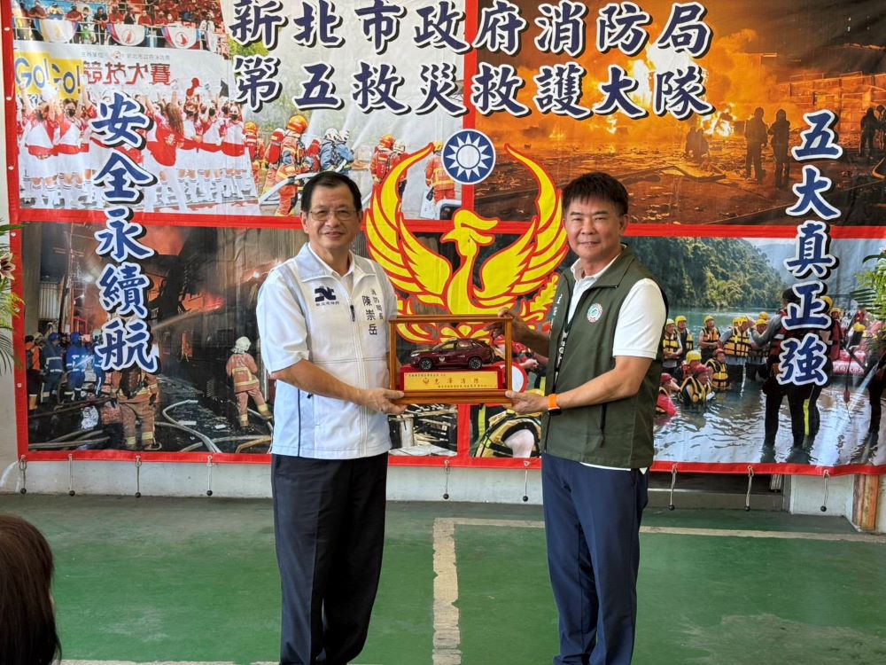 《圖說》新北消局長陳崇岳〈左〉回贈模型車予巨輪興業公司董事長陳正忠。〈消防局提供〉