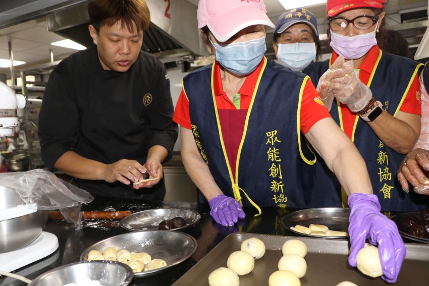 贈送獨居長輩及國小弱勢生 眾能協會攜手黎明外籍生手作蛋黃酥 4 《圖說》黎明技術學院餐飲管理系劉子賓老師(左)指導眾能志工如何包餡。〈社會局提供〉