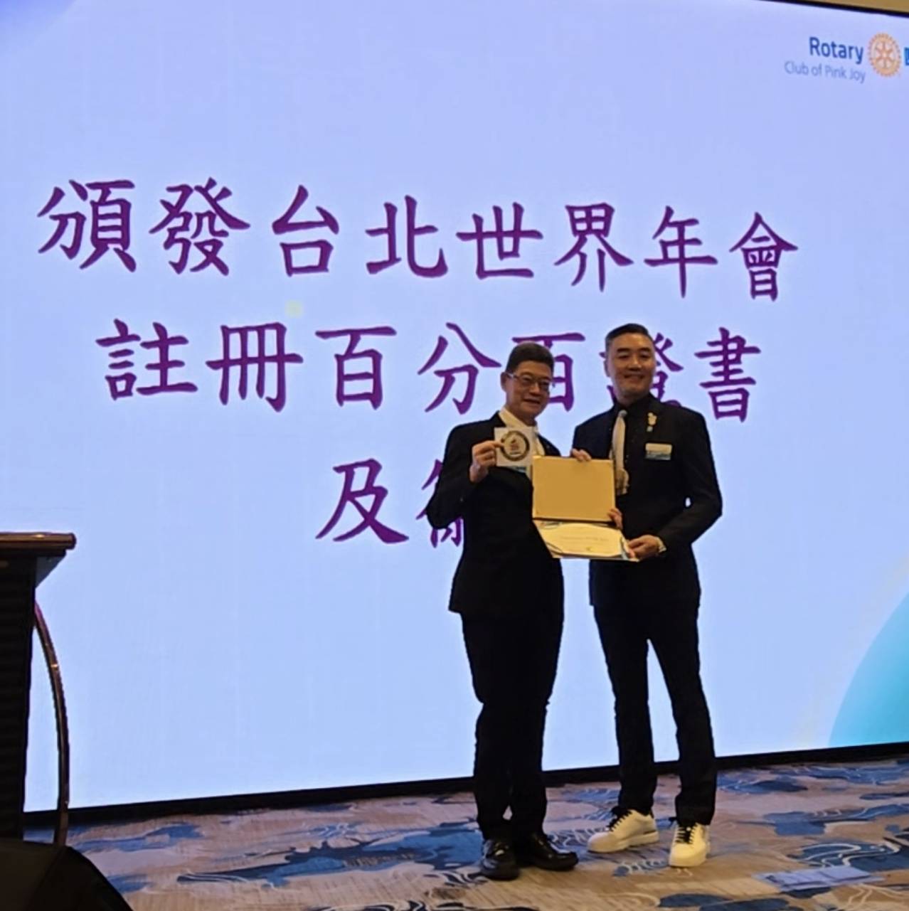 3502地區總監張玉斌（DG Daniel）頒發台北世界年會註冊百分百證書及徽章于社長張智淵。（記者 趙靜姸攝）