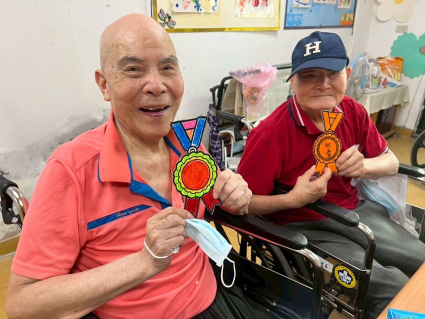 《圖說》八德榮家養護堂周伯伯(左1)完成手繪自製獎牌十分開心。〈八德榮家提供〉