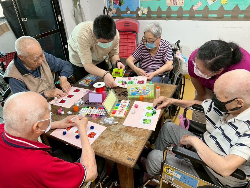 《圖說》中山醫學大學社工實習生(後排左2)用心帶領住民長輩藝術創作。〈八德榮家提供〉