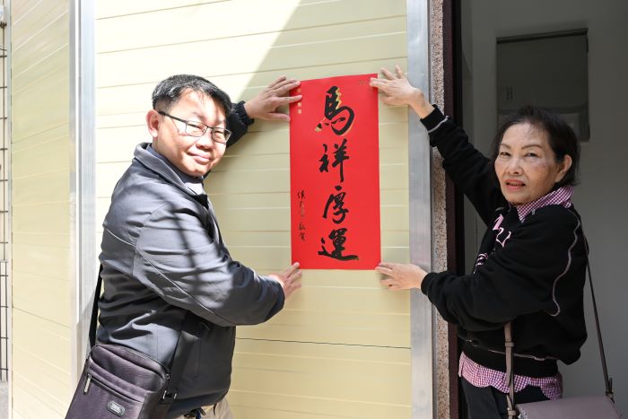 《圖說》建築師與住戶一同將春聯張貼在電梯門口。〈城鄉局提供〉