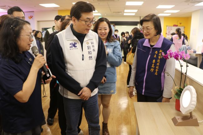 《圖說》五股成州身障日照中心主任江明芬(左1)為劉和然介紹採用40赫茲(Hz)的貝殼燈,可穩定心智障礙者的情緒。〈社會局提供〉