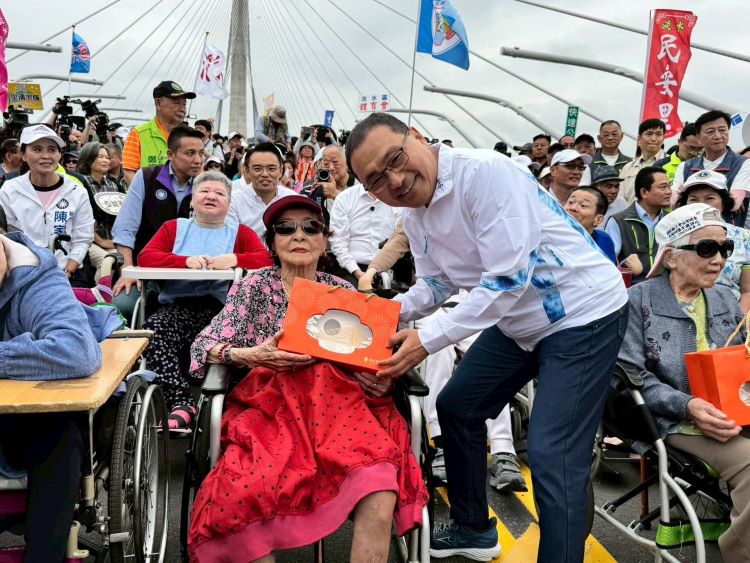 《圖說》侯友宜向人瑞阿嬤致意，並致贈淡江大橋意象燈飾祝福。〈民政局提供〉