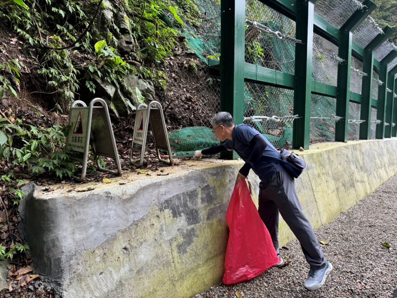 《圖說》參加淨山活動的台電員工手持長夾，沿路清除山徑上的垃圾。〈北西區處提供〉